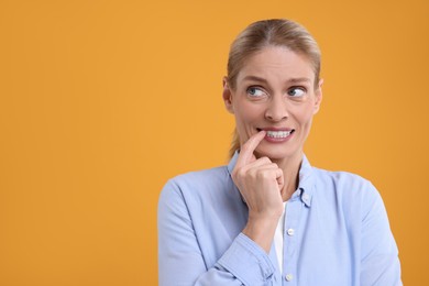 Photo of Embarrassed woman on orange background. Space for text
