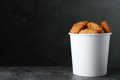 Bucket with delicious chicken nuggets on grey background. Space for text