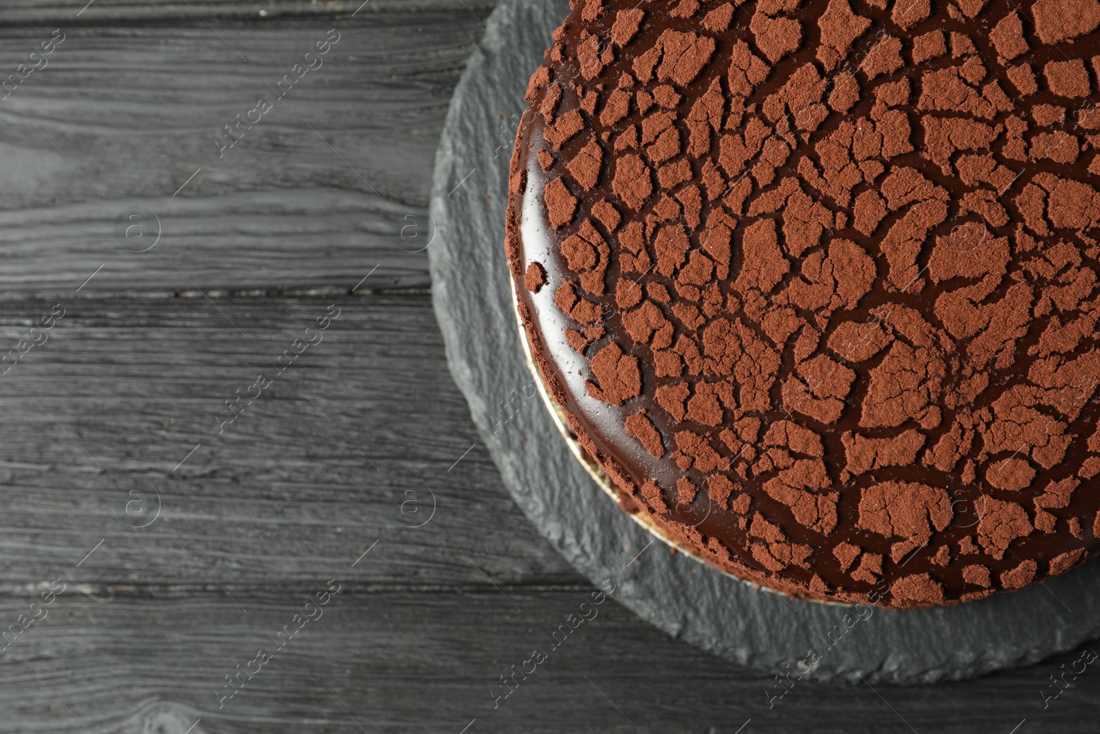 Photo of Delicious chocolate truffle cake on black wooden table, top view. Space for text