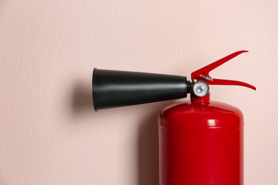 Fire extinguisher on pink background, closeup view