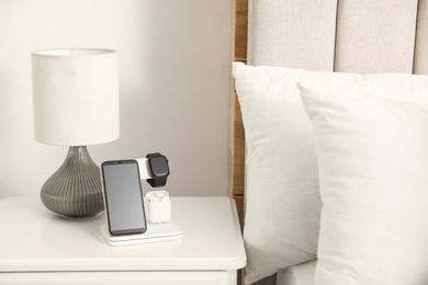 Photo of Different gadgets charging on wireless pad in bedroom