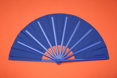 Photo of Bright blue hand fan on orange background, top view