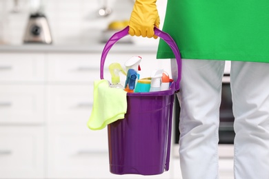 Photo of Man in uniform with cleaning supplies indoors