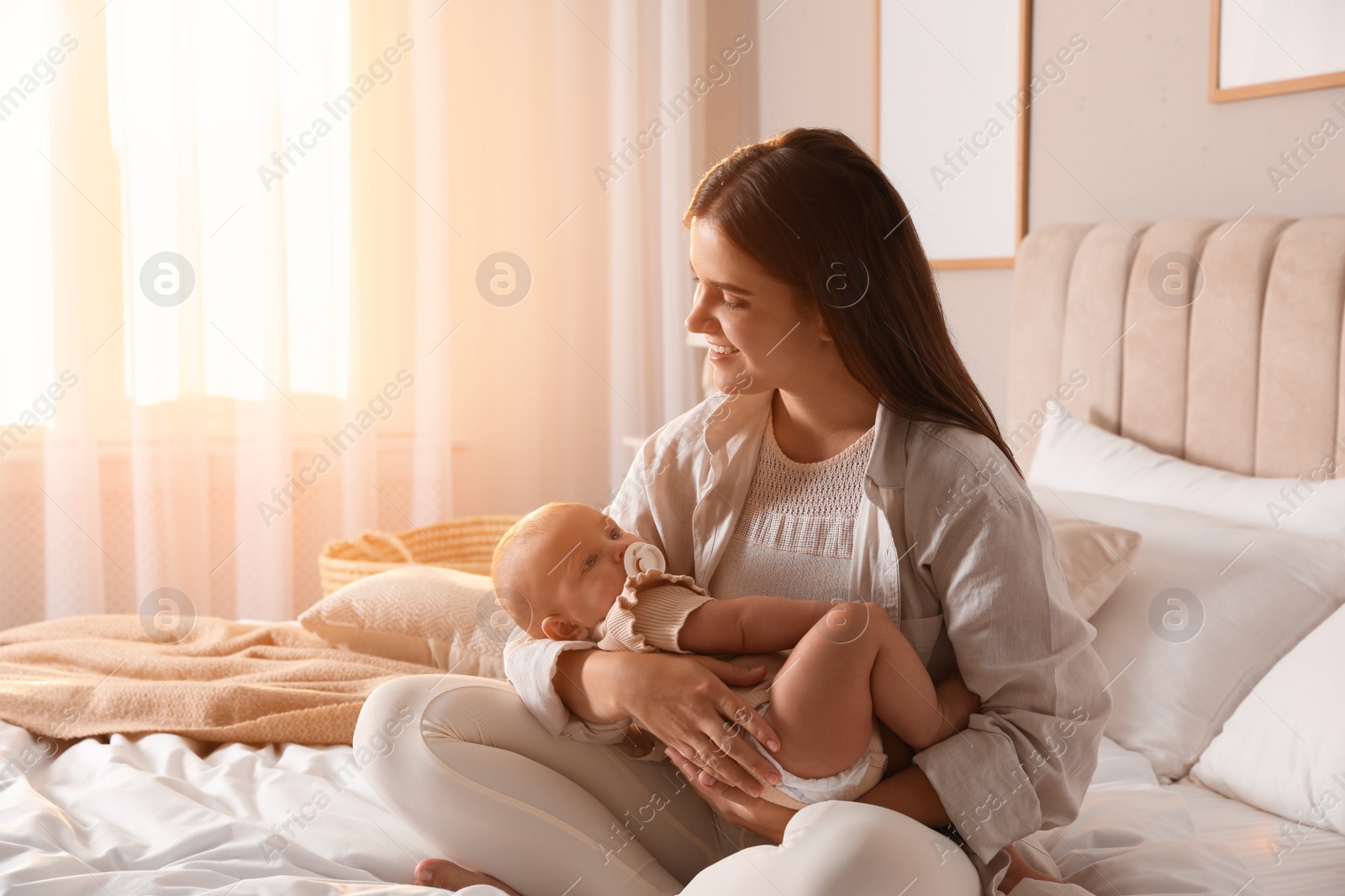 Photo of Young woman with her little baby on bed at home
