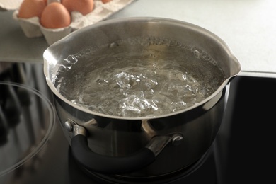 Photo of Pot with boiling water on electric stove in kitchen