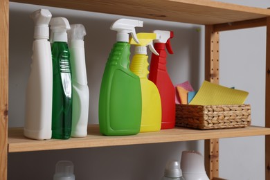 Photo of Different detergents and rags on wooden rack in laundry room