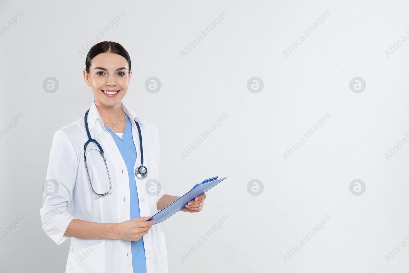 Photo of Portrait of young doctor with stethoscope and clipboard on white background