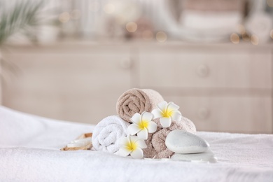 Photo of Towels and candles on massage table in modern spa salon. Place for relaxation