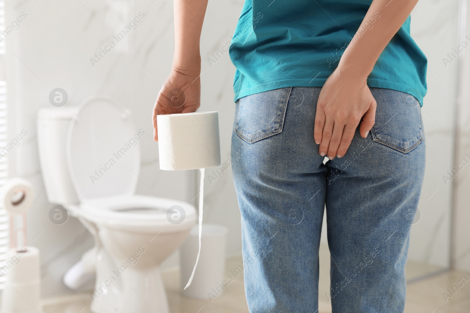 Photo of Woman with toilet paper suffering from hemorrhoid in rest room, closeup