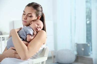 Photo of Young woman with her newborn baby at home. Space for text