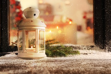 Image of Lantern with candle and fir branches near window outdoors. Christmas eve 