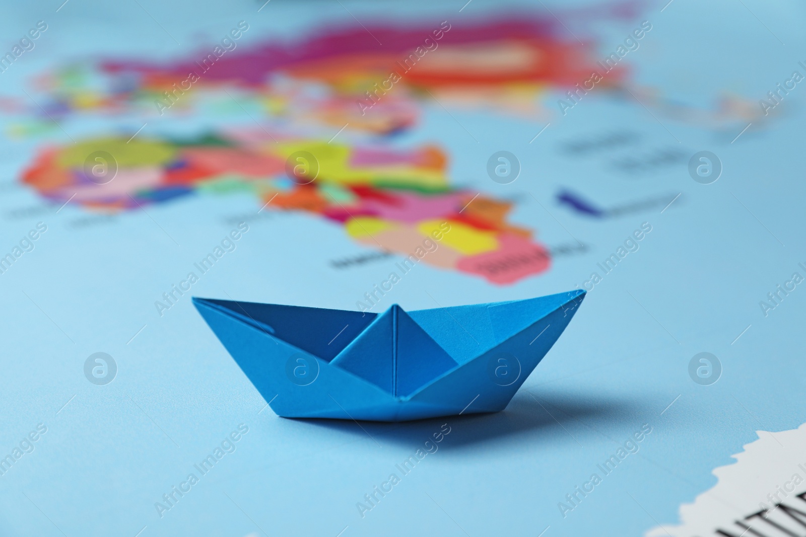 Photo of Light blue paper boat on world map, closeup