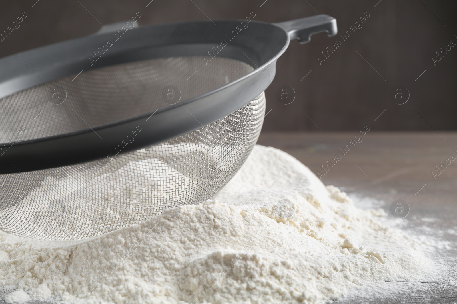 Photo of Sieve and pile of flour on table, closeup