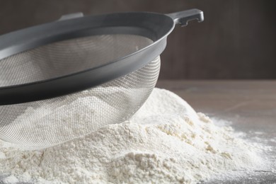 Sieve and pile of flour on table, closeup