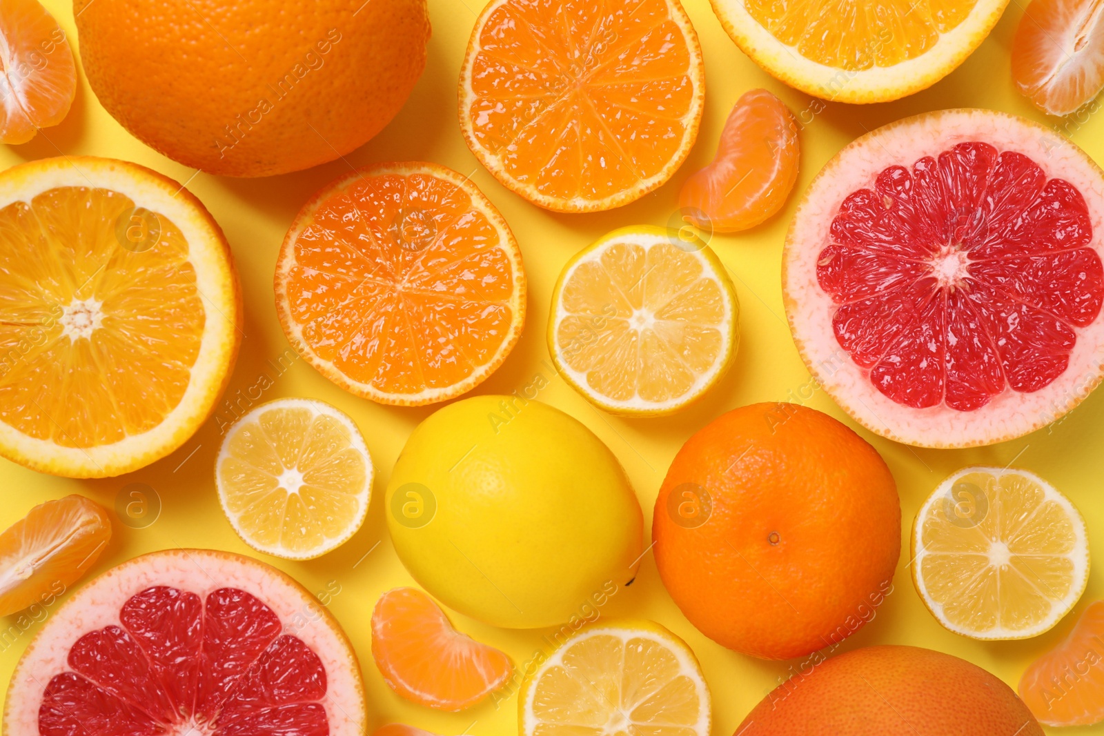 Photo of Many fresh citrus fruits on yellow background, flat lay