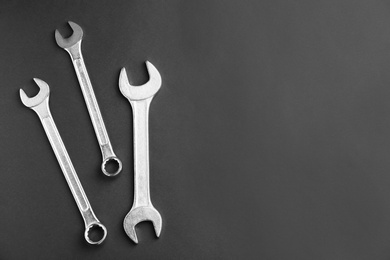 New wrenches on grey background, top view with space for text. Plumber tools