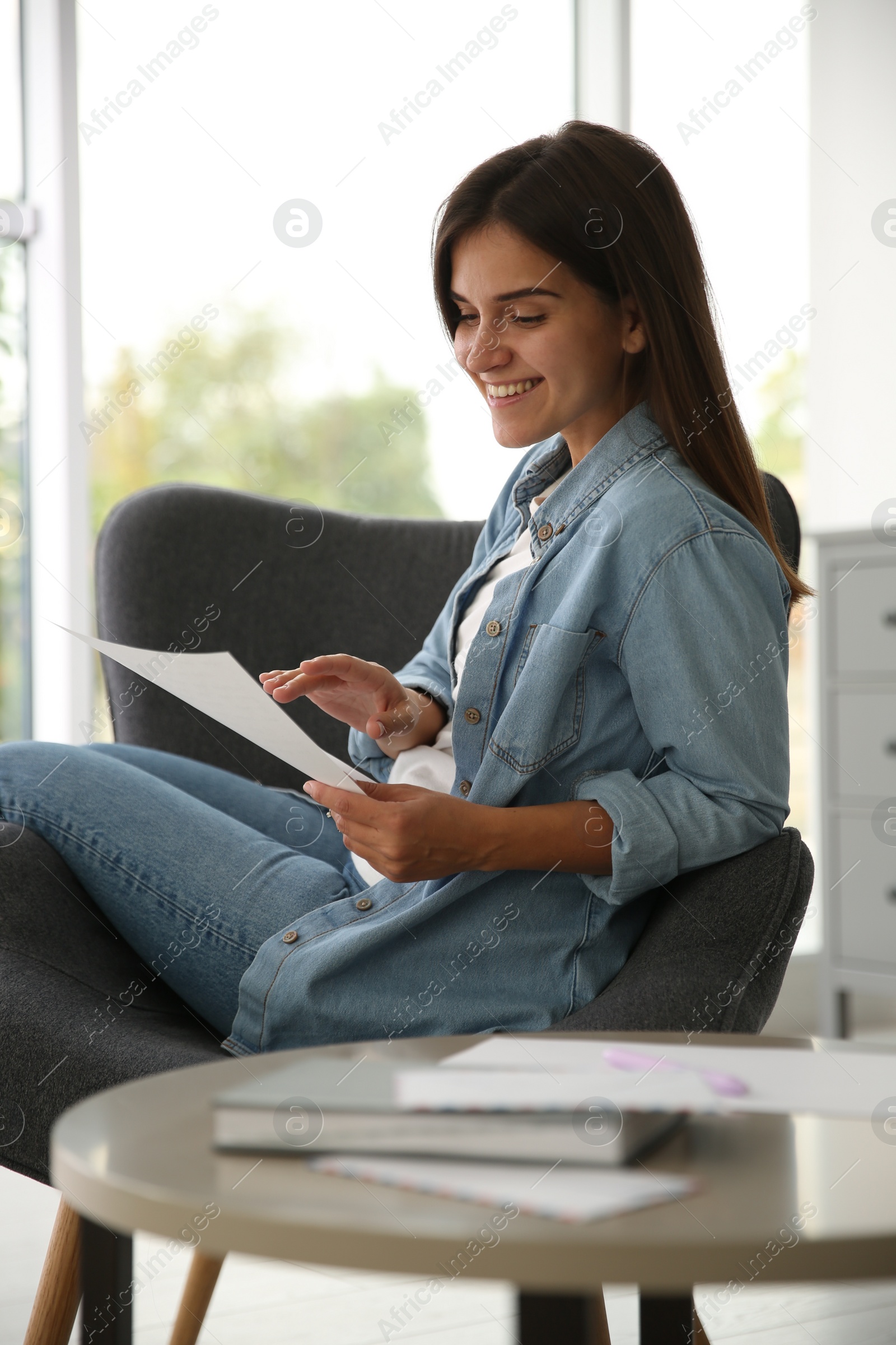 Photo of Young woman reading paper letter at home