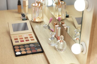 Cosmetic products and perfumes on wooden dressing table in makeup room