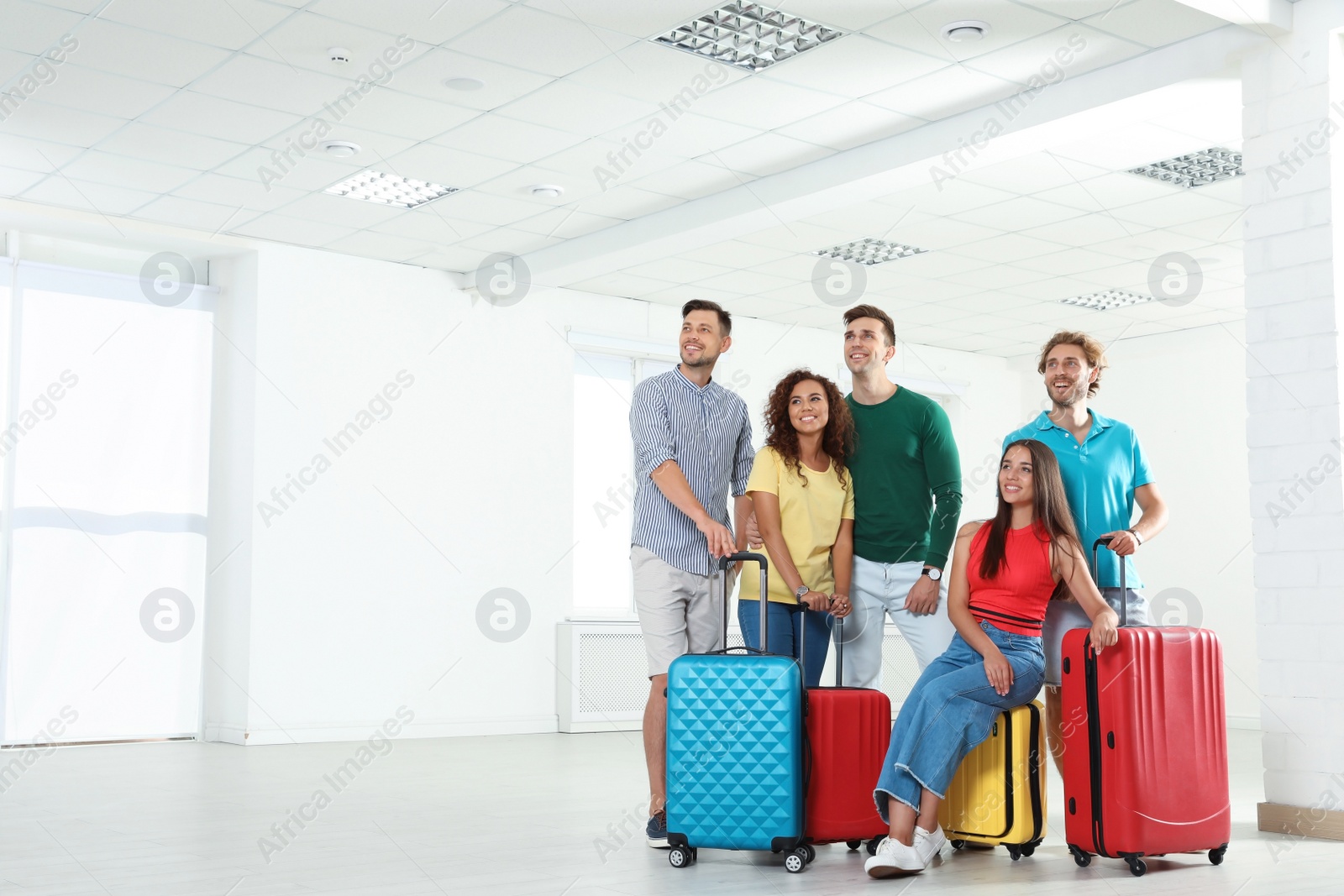 Photo of Group of young people with suitcases in light room