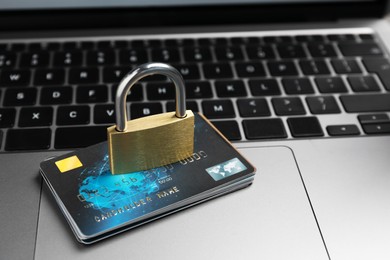 Cyber security. Metal padlock and credit cards on laptop, closeup