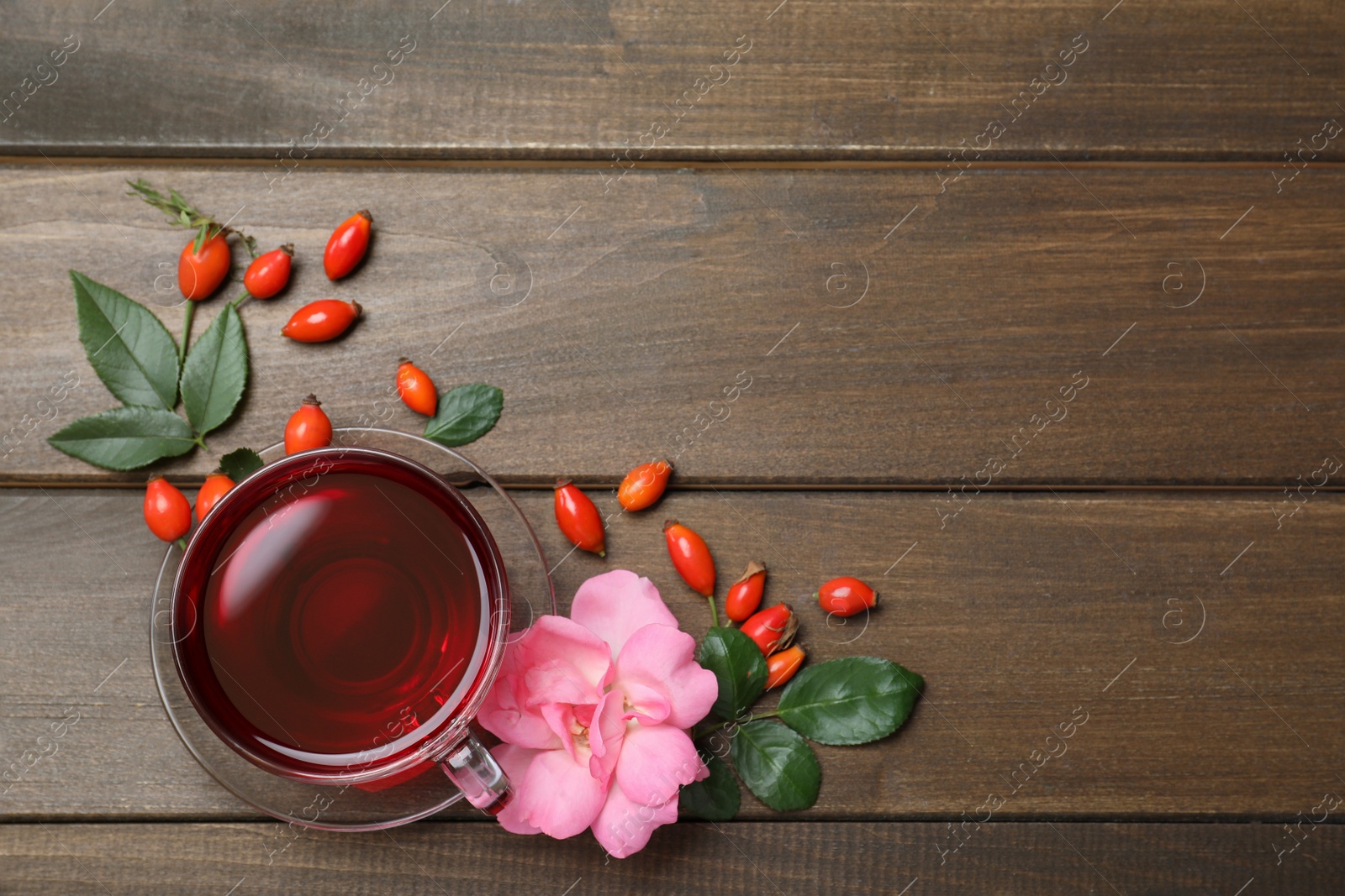 Photo of Flat lay composition with aromatic rose hip tea on wooden table. Space for text