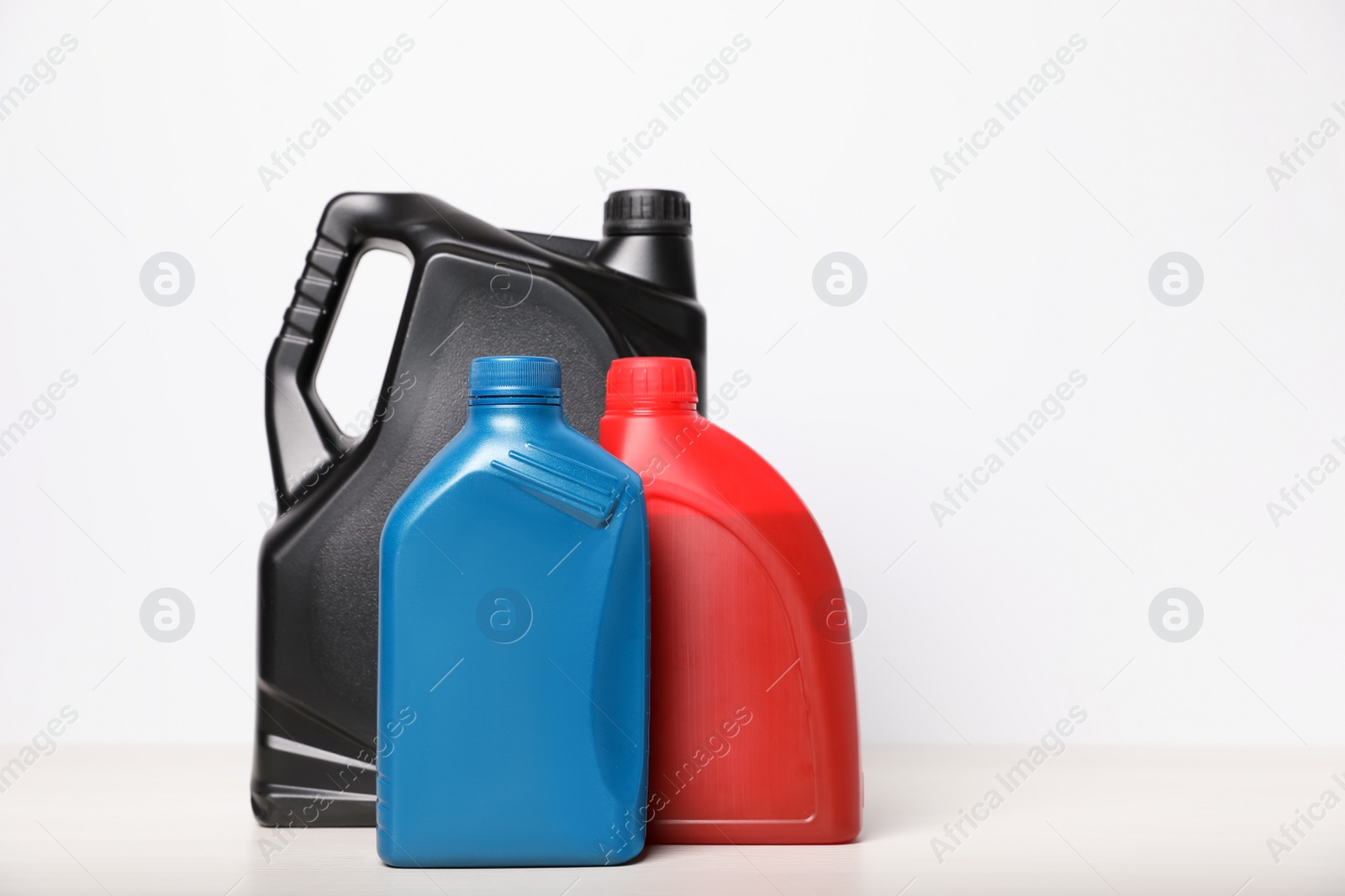 Photo of Motor oil in different canisters on table against white background, space for text