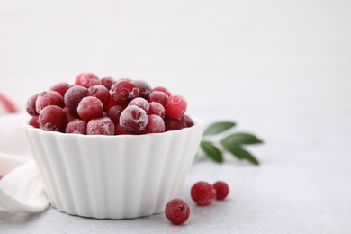 Photo of Frozen red cranberries in bowl on light table, closeup. Space for text