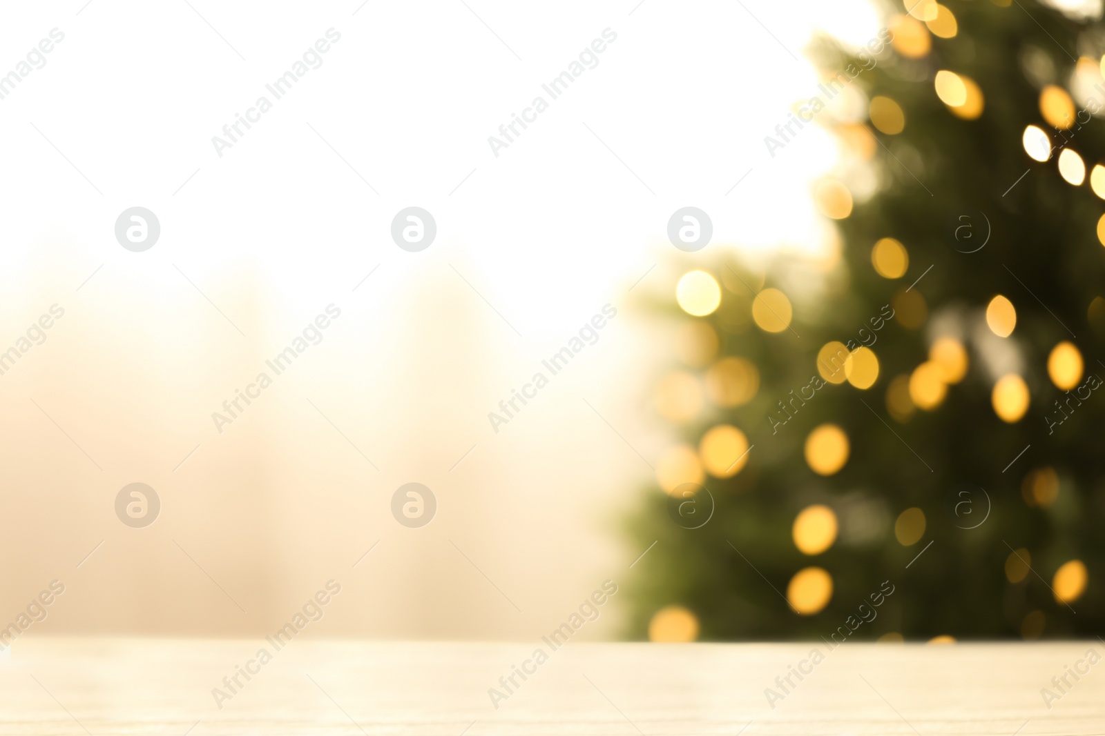 Photo of Empty table and blurred fir tree with yellow Christmas lights on background, bokeh effect. Space for design