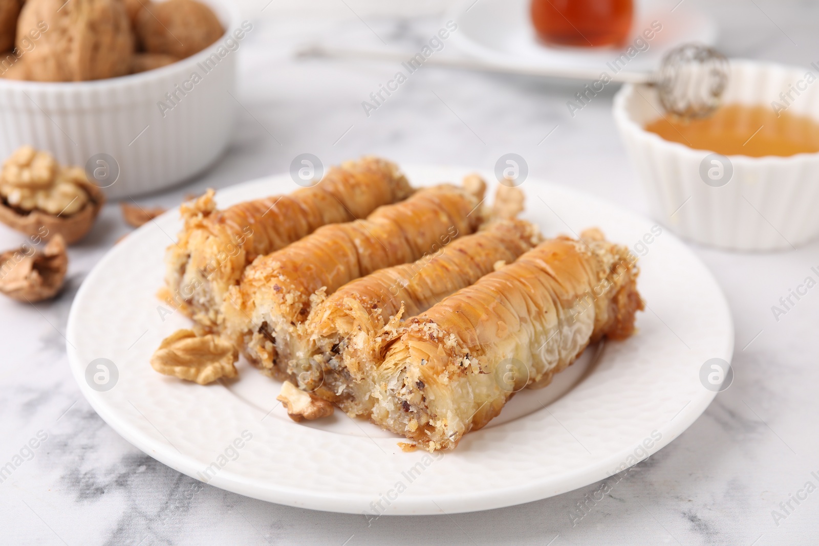 Photo of Eastern sweets. Pieces of tasty baklava on white marble table, closeup