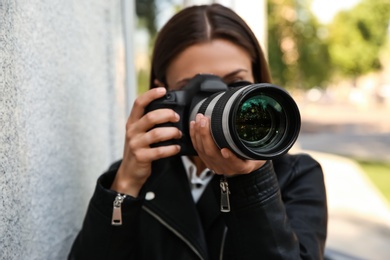 Photo of Private detective with camera spying near building on city street