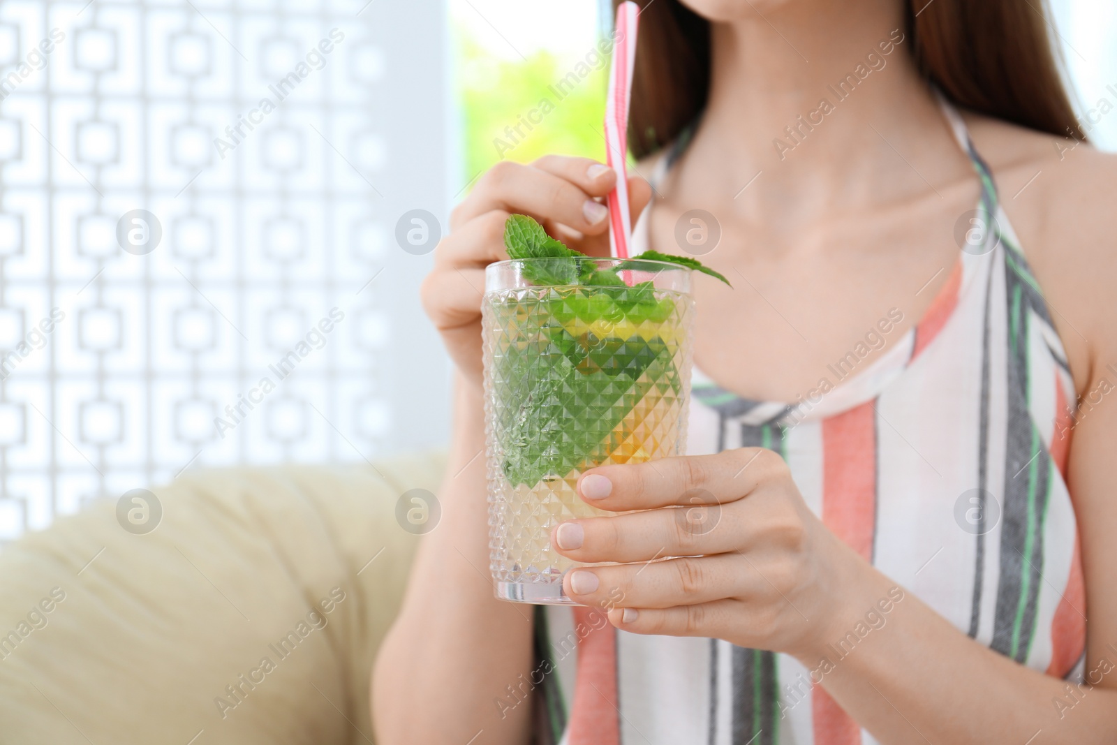 Photo of Woman with glass of natural detox lemonade near window at home. Space for text