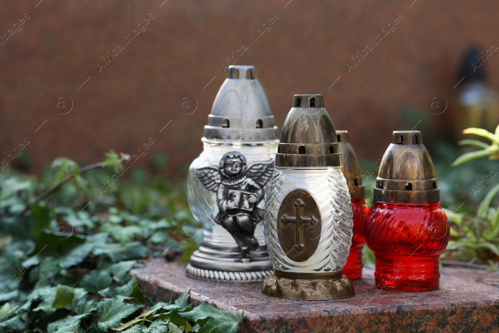 Photo of Grave lanterns and ivy near tombstone in cemetery