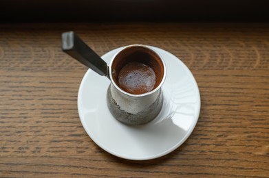 Jezve with fresh coffee on wooden table, above view