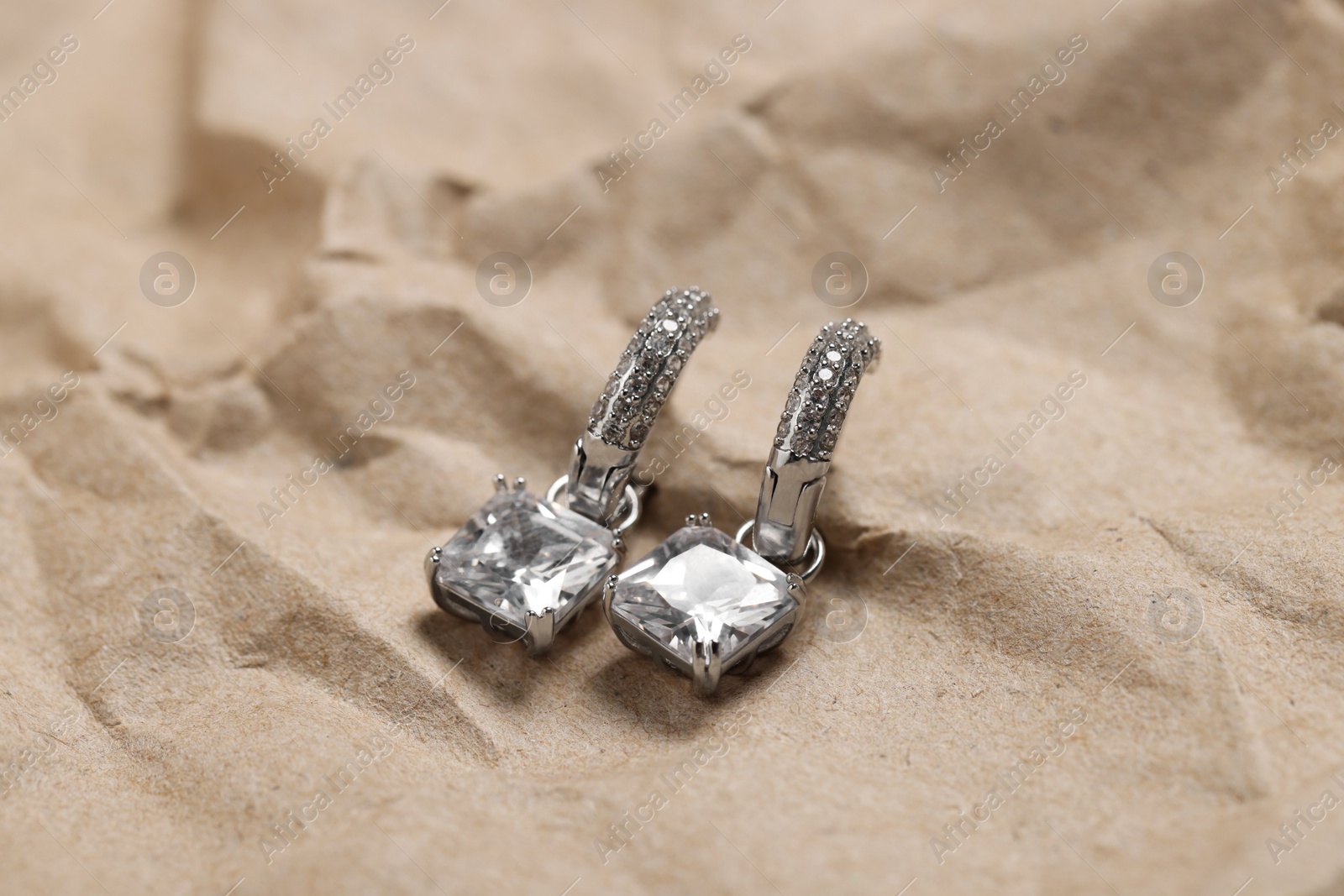 Photo of Beautiful earrings on kraft paper. Luxury jewelry