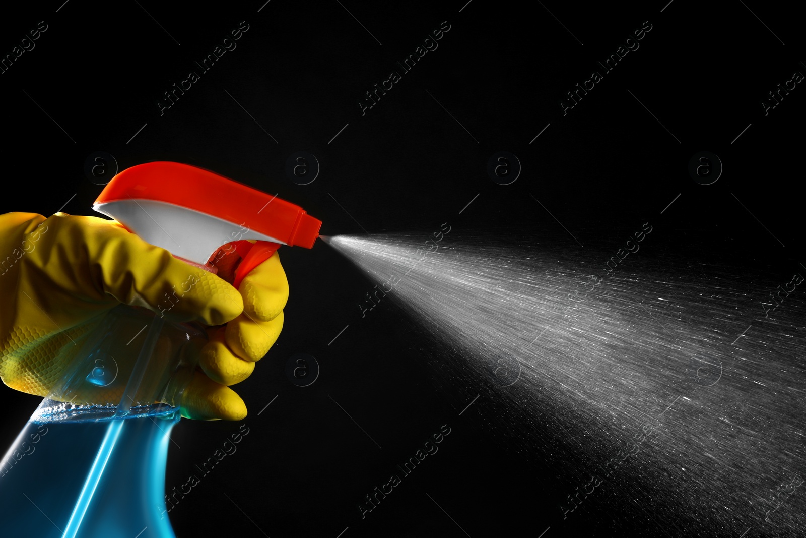 Photo of Woman spraying liquid from bottle on black background, closeup