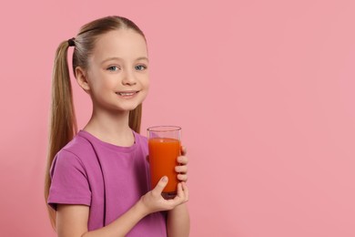 Photo of Cute little girl with glass of fresh juice on pink background, space for text