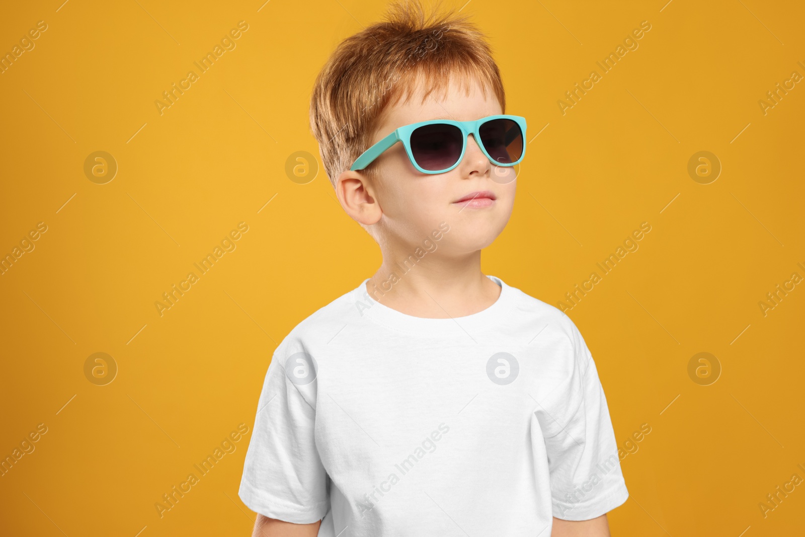 Photo of Cute little boy with sunglasses on yellow background