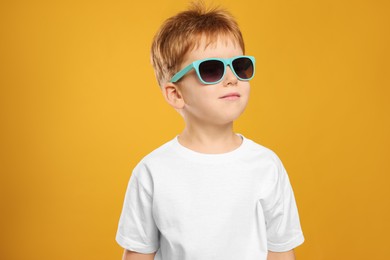 Photo of Cute little boy with sunglasses on yellow background