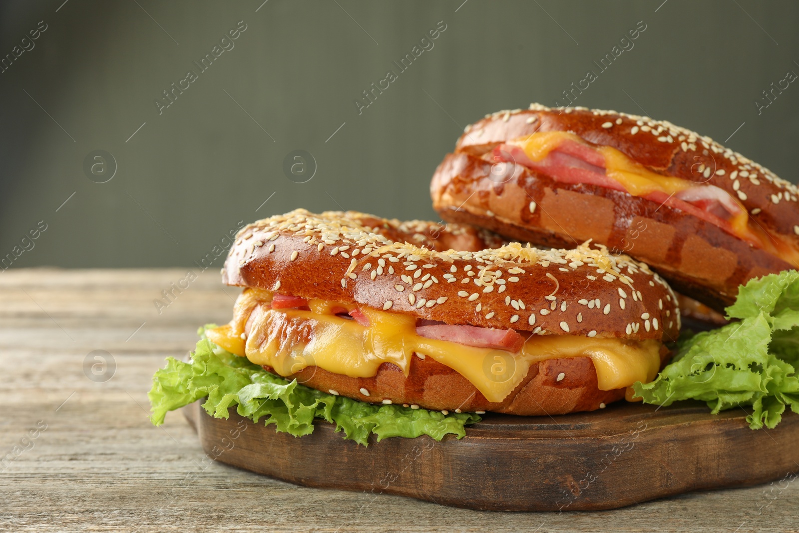 Photo of Delicious bagels with ham and cheese on wooden table, space for text