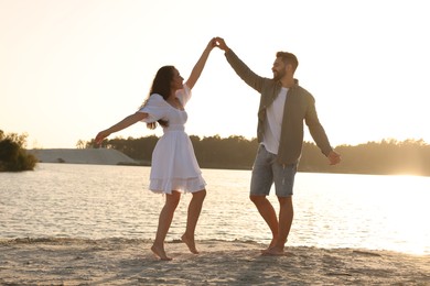 Happy couple dancing near river on sunny day