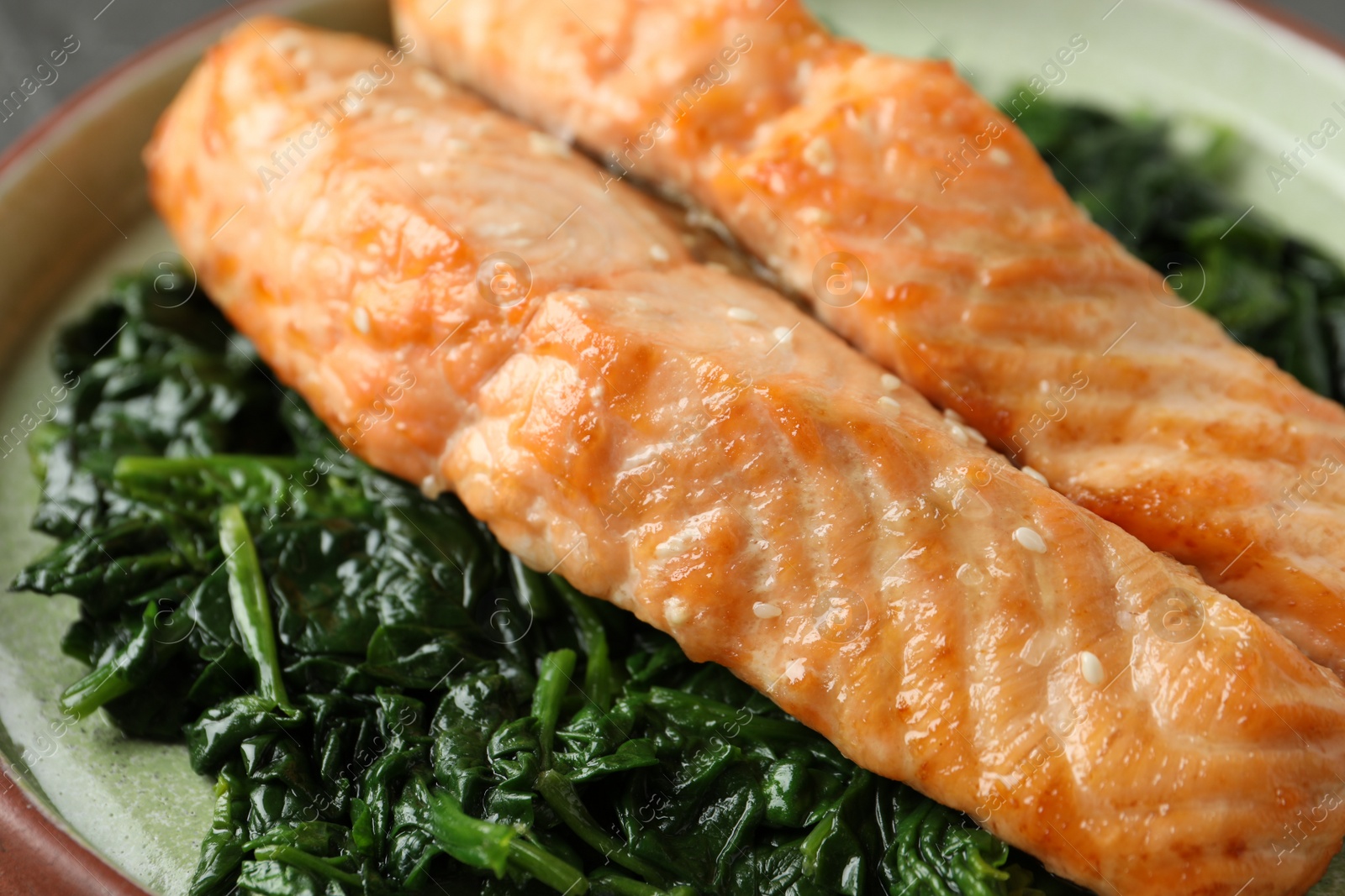 Photo of Tasty salmon with spinach on plate, closeup