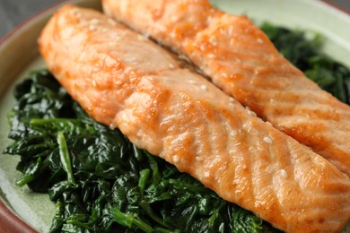 Photo of Tasty salmon with spinach on plate, closeup