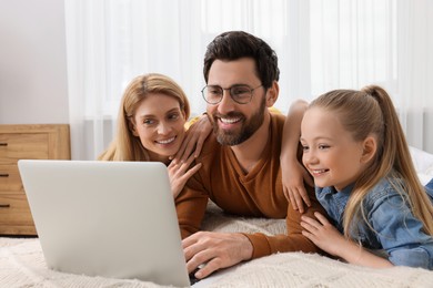 Photo of Happy family with laptop on bed at home