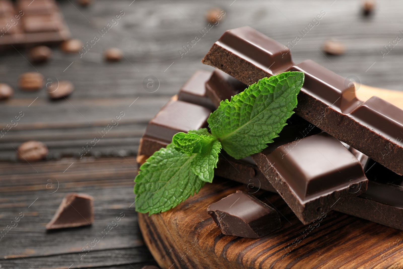 Photo of Pieces of dark chocolate with mint on wooden table