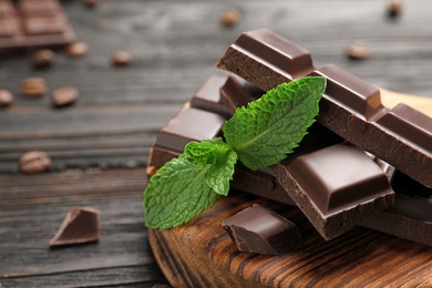 Pieces of dark chocolate with mint on wooden table