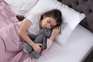 Photo of Beautiful little girl with toy rabbit sleeping in bed