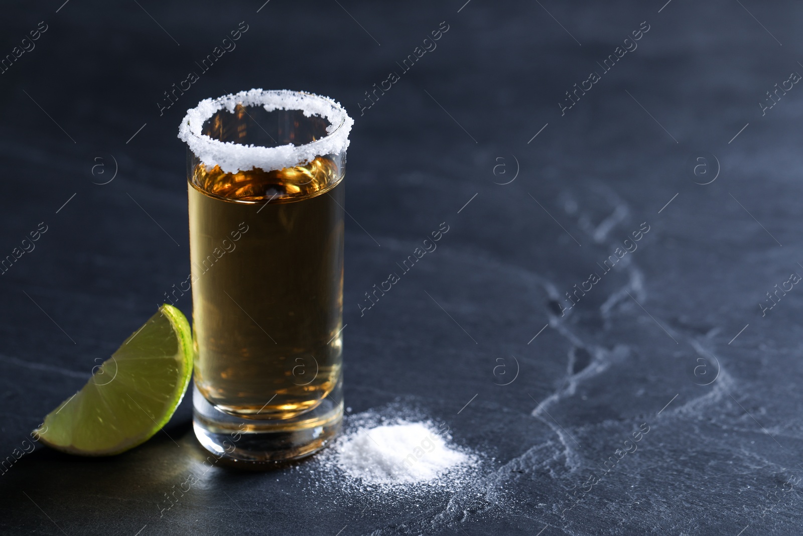 Photo of Mexican Tequila shot, lime slice and salt on grey table. Space for text