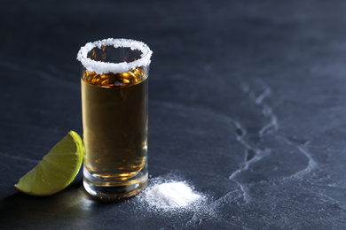 Mexican Tequila shot, lime slice and salt on grey table. Space for text