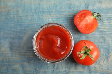 Photo of Jar with homemade tomato sauce and fresh vegetables on wooden table, top view