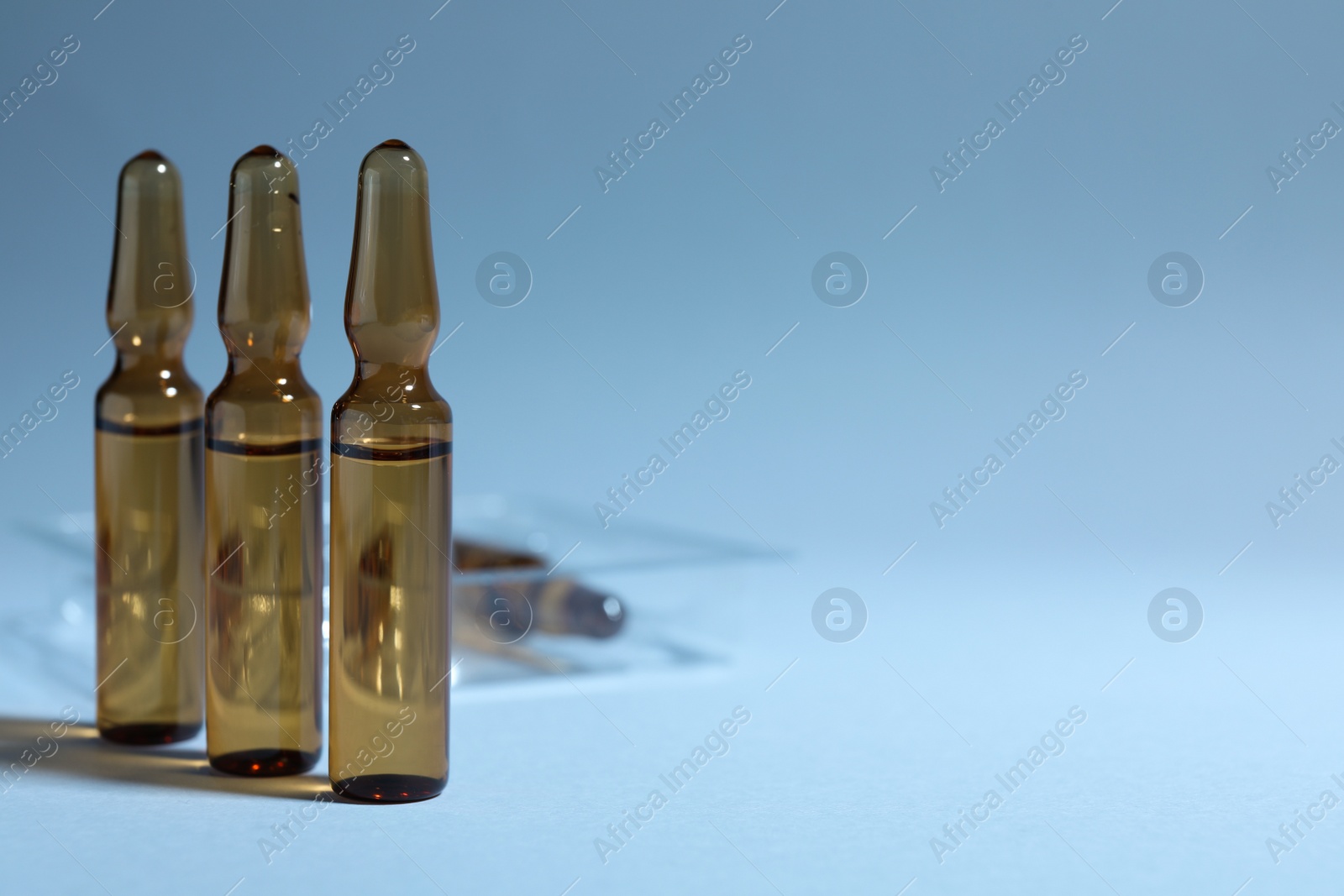 Photo of Brown pharmaceutical ampoules with medication on light background. Space for text